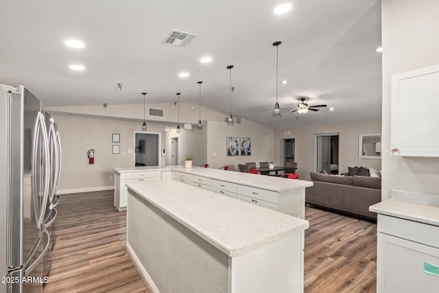 kitchen with freestanding refrigerator, a spacious island, light wood finished floors, vaulted ceiling, and recessed lighting