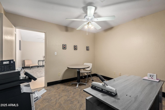 office area featuring a ceiling fan, dark colored carpet, and baseboards