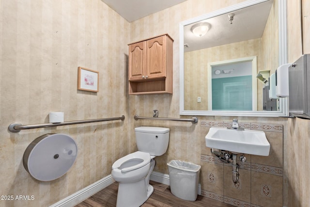 half bath featuring a sink, toilet, and wood finished floors