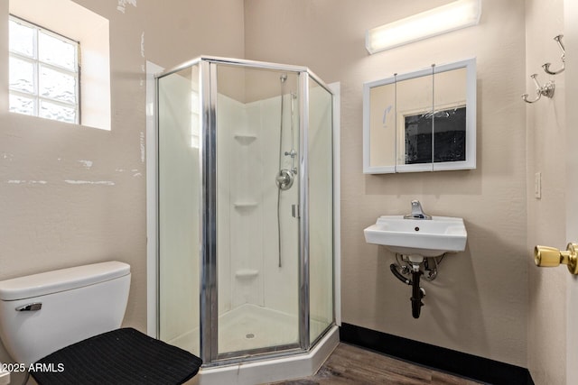 full bathroom with a shower stall, toilet, and wood finished floors
