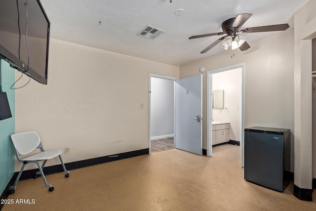 unfurnished bedroom with refrigerator, baseboards, light floors, and connected bathroom