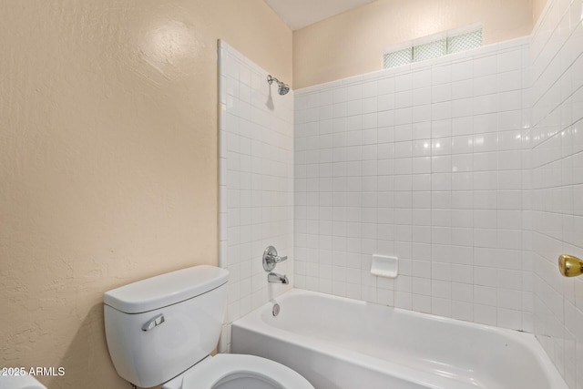 full bathroom with a textured wall, toilet, and tub / shower combination