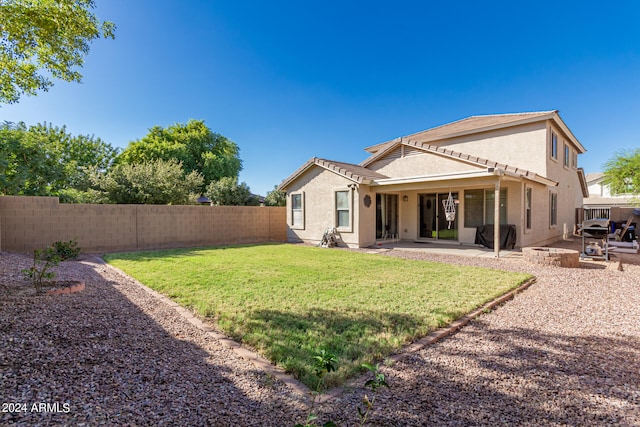 back of house with a patio and a lawn