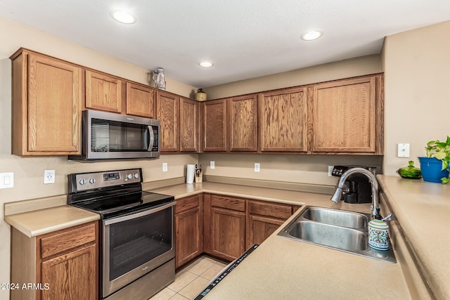 kitchen featuring stainless steel appliances, sink, and light tile patterned floors