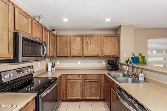 kitchen with stainless steel appliances, sink, and light tile patterned floors