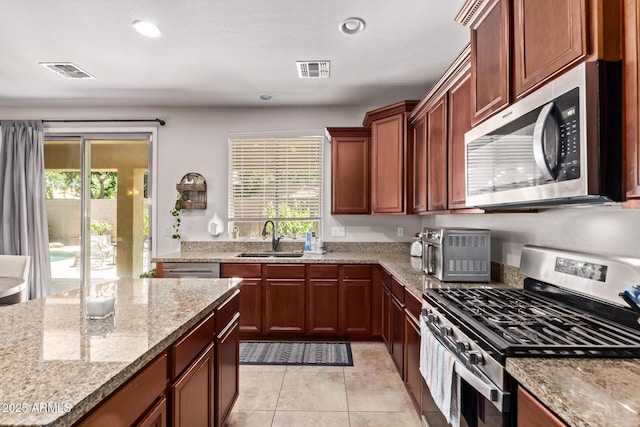 7031 W Lone Tree Trl, Peoria, AZ 85383 - kitchen featuring appliances with stainless steel finishes, healthy amount of natural light, light tile patterned floors, light stone counters, and recessed lighting