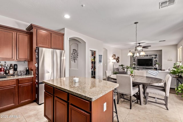 7031 W Lone Tree Trl, Peoria, AZ 85383 - kitchen with freestanding refrigerator, arched walkways, a ceiling fan, a kitchen island, and open floor plan