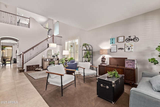 7031 W Lone Tree Trl, Peoria, AZ 85383 - living area with arched walkways, tile patterned floors, stairs, and a high ceiling