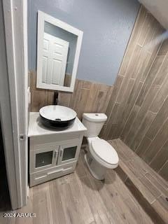 bathroom featuring toilet, a tile shower, vanity, and wood-type flooring