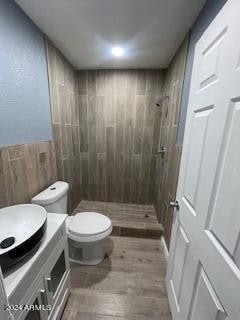 bathroom with vanity, hardwood / wood-style floors, toilet, and tiled shower