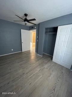 unfurnished bedroom featuring a closet, dark hardwood / wood-style floors, and ceiling fan