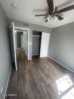 unfurnished bedroom with dark hardwood / wood-style floors, a closet, and ceiling fan