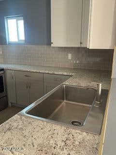 kitchen featuring white cabinetry, light stone countertops, sink, and stainless steel stove