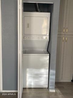 laundry area featuring stacked washer and dryer and dark hardwood / wood-style flooring