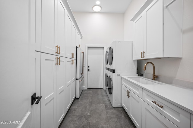 laundry room with stacked washer / drying machine, cabinet space, and a sink