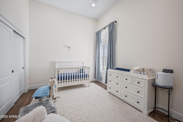 bedroom featuring recessed lighting, a closet, wood finished floors, a nursery area, and baseboards