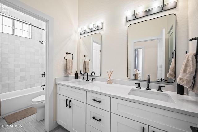 full bathroom featuring double vanity, bathing tub / shower combination, a sink, and toilet