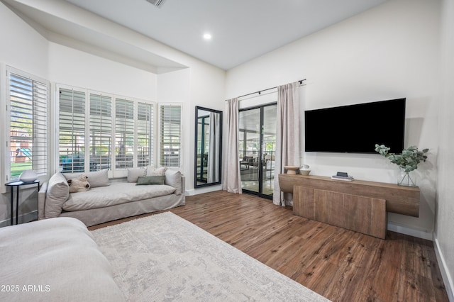 living area with baseboards, wood finished floors, and recessed lighting