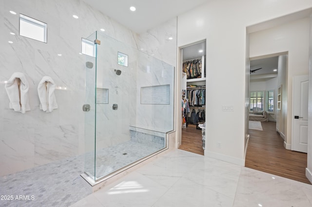 bathroom featuring a marble finish shower, baseboards, marble finish floor, a walk in closet, and recessed lighting