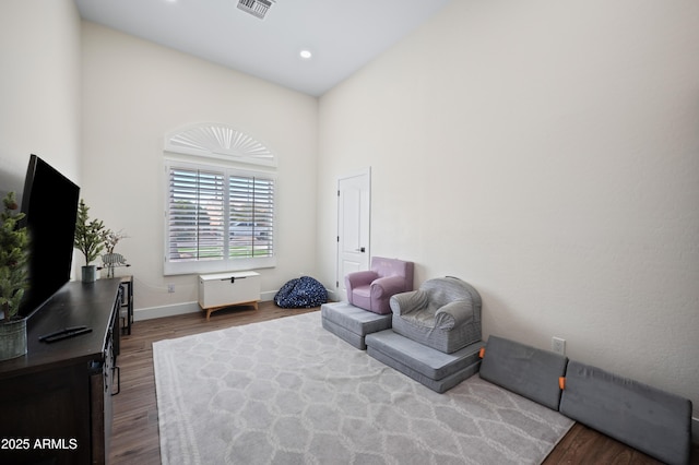 living area with dark wood-style flooring, recessed lighting, visible vents, a high ceiling, and baseboards