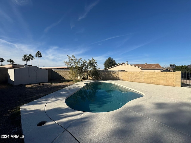 view of swimming pool featuring a shed and a patio area