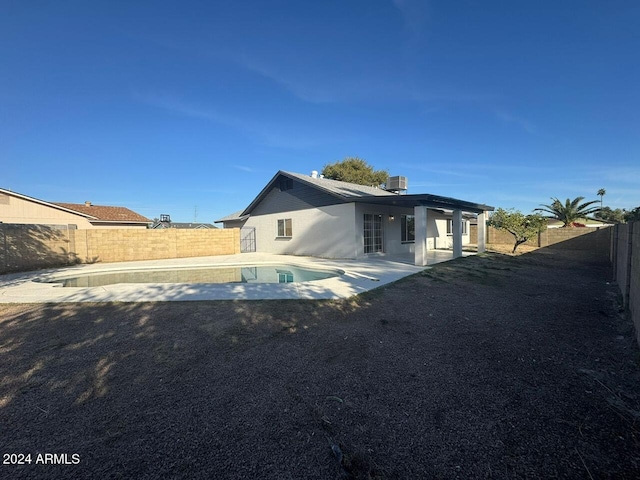 back of property featuring a patio, a fenced in pool, and central AC