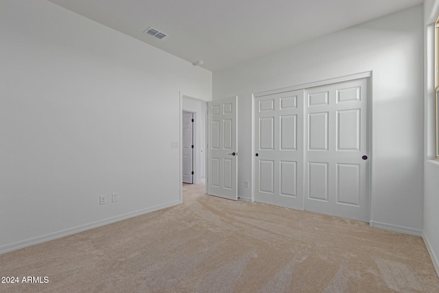 unfurnished bedroom with light carpet and a closet