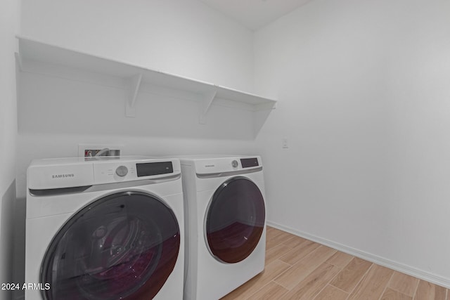 laundry room with separate washer and dryer and light hardwood / wood-style flooring