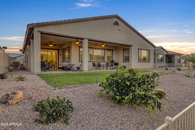 back house at dusk featuring a patio and ceiling fan