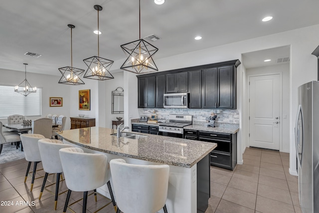 kitchen with appliances with stainless steel finishes, sink, a kitchen breakfast bar, and a center island with sink