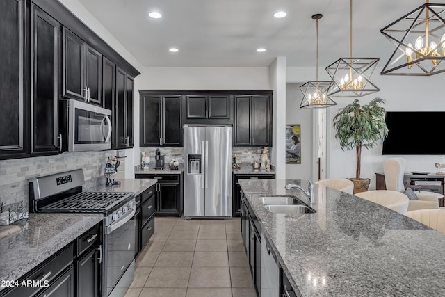 kitchen with decorative light fixtures, a notable chandelier, appliances with stainless steel finishes, sink, and stone counters