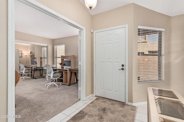 entrance foyer with baseboards, light tile patterned floors, and light colored carpet