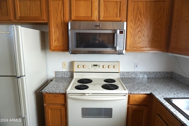 kitchen with light stone countertops, sink, and white appliances