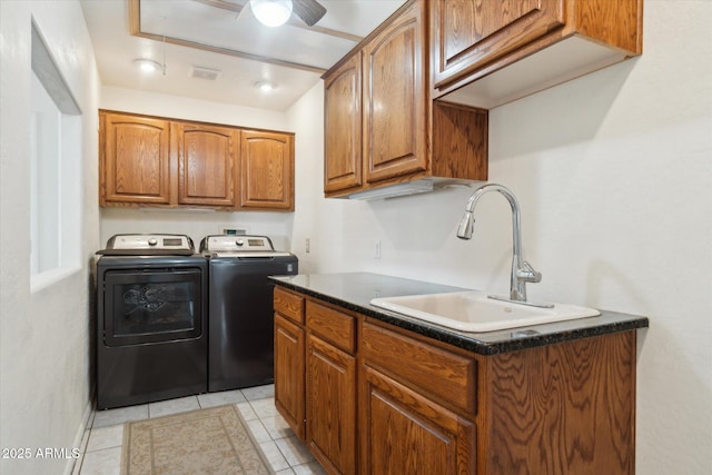 laundry area with independent washer and dryer, cabinets, sink, and light tile patterned floors