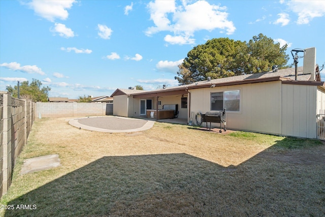 back of house with a patio area, a hot tub, and a lawn