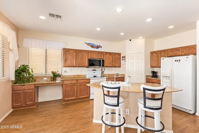 3381 E Canary Way, Chandler, AZ 85286 - kitchen featuring white appliances, brown cabinetry, a kitchen breakfast bar, light wood-style flooring, and a center island with sink
