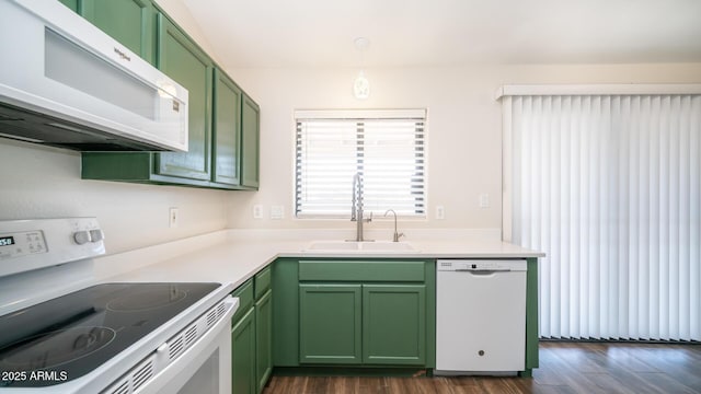 kitchen with white appliances, hanging light fixtures, green cabinetry, dark hardwood / wood-style flooring, and sink