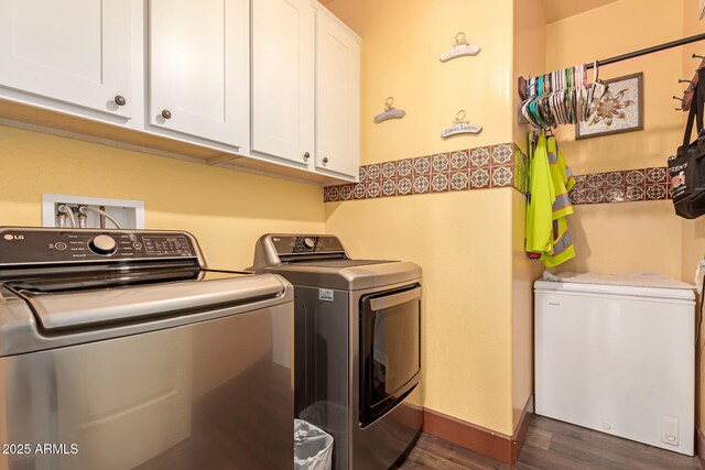 laundry area with dark wood-type flooring, cabinets, and washer and clothes dryer