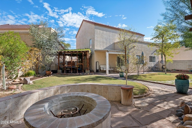 rear view of house featuring a yard, a patio, and an outdoor fire pit