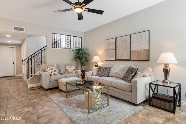 living room featuring baseboards, stairway, visible vents, and a ceiling fan