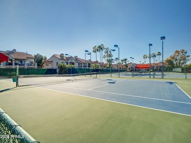 view of tennis court featuring a residential view and fence