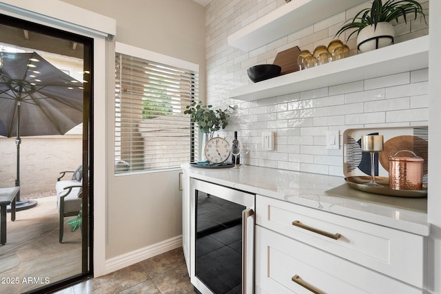 kitchen with decorative backsplash, wine cooler, light stone countertops, white cabinetry, and open shelves