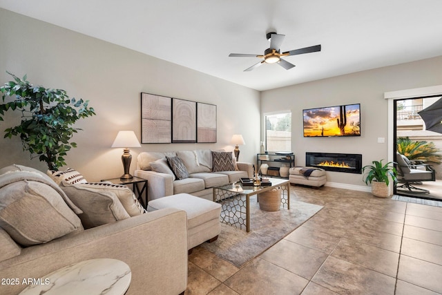 living area with ceiling fan, light tile patterned floors, a glass covered fireplace, and baseboards