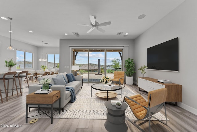 living room with ceiling fan with notable chandelier and light hardwood / wood-style flooring