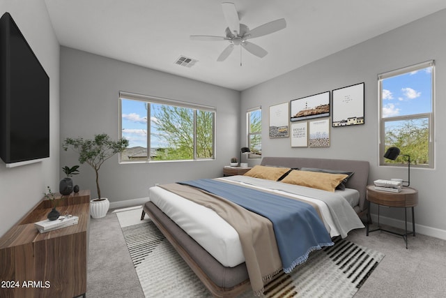 bedroom featuring multiple windows, ceiling fan, and light colored carpet