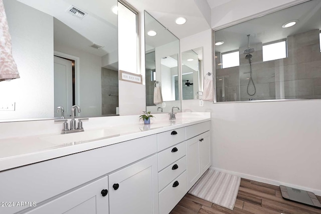 bathroom with hardwood / wood-style flooring, vanity, and a tile shower