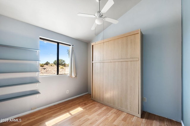 unfurnished bedroom featuring a ceiling fan, light wood-style flooring, baseboards, and lofted ceiling