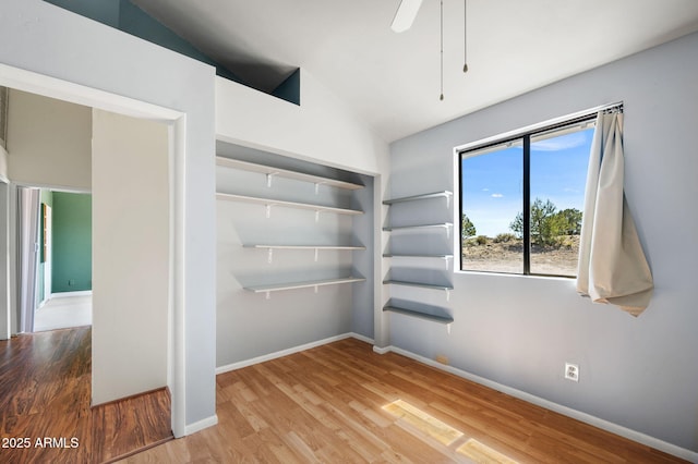 interior space with baseboards, ceiling fan, wood finished floors, and vaulted ceiling