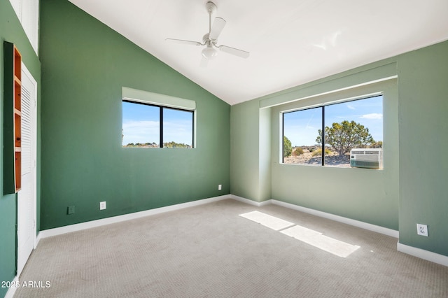 empty room with carpet flooring, a ceiling fan, baseboards, and vaulted ceiling