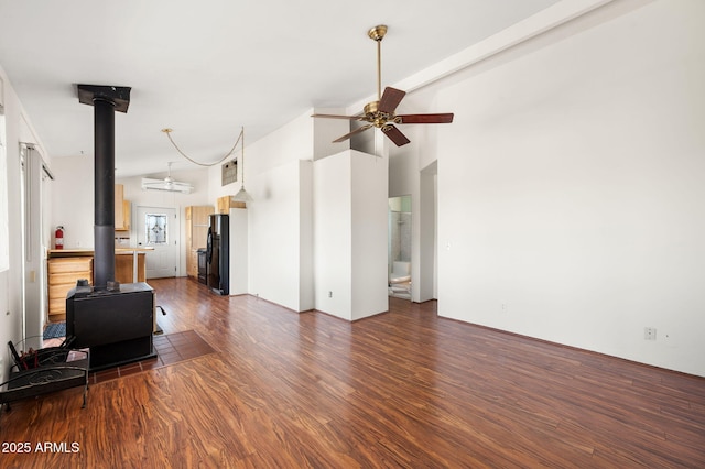 unfurnished living room featuring dark wood-type flooring, high vaulted ceiling, a wood stove, and a ceiling fan